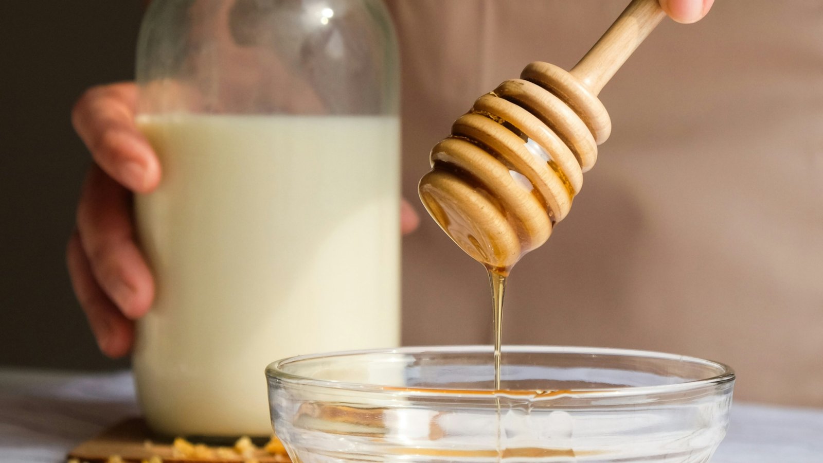 Drewniany stół z daniami przygotowanymi z miodem Pasieki Mnich kurczak sałatka i deser malinowy z otwartymi słoikami miodu obok