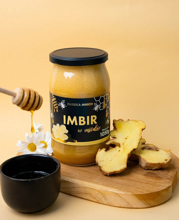 Miód kremowany z imbirem 500g Pasieka Mnich obok świeżego korzenia imbiru i rumianku.